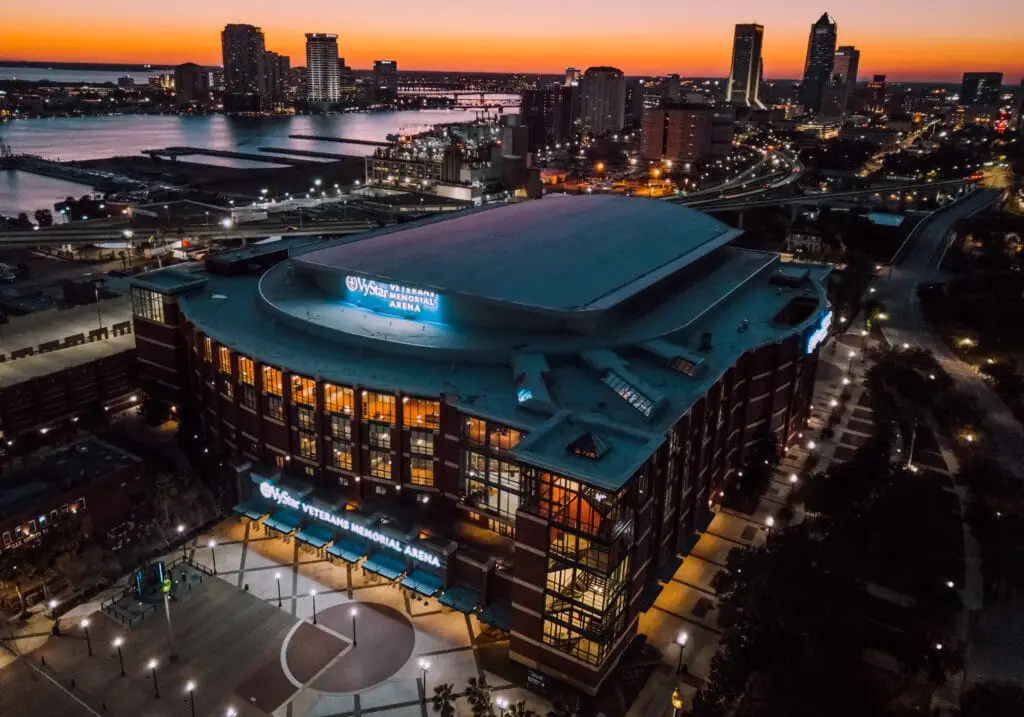 Exterior view of Jacksonville Veterans Memorial Arena with modern architecture and large glass windows on a sunny day.