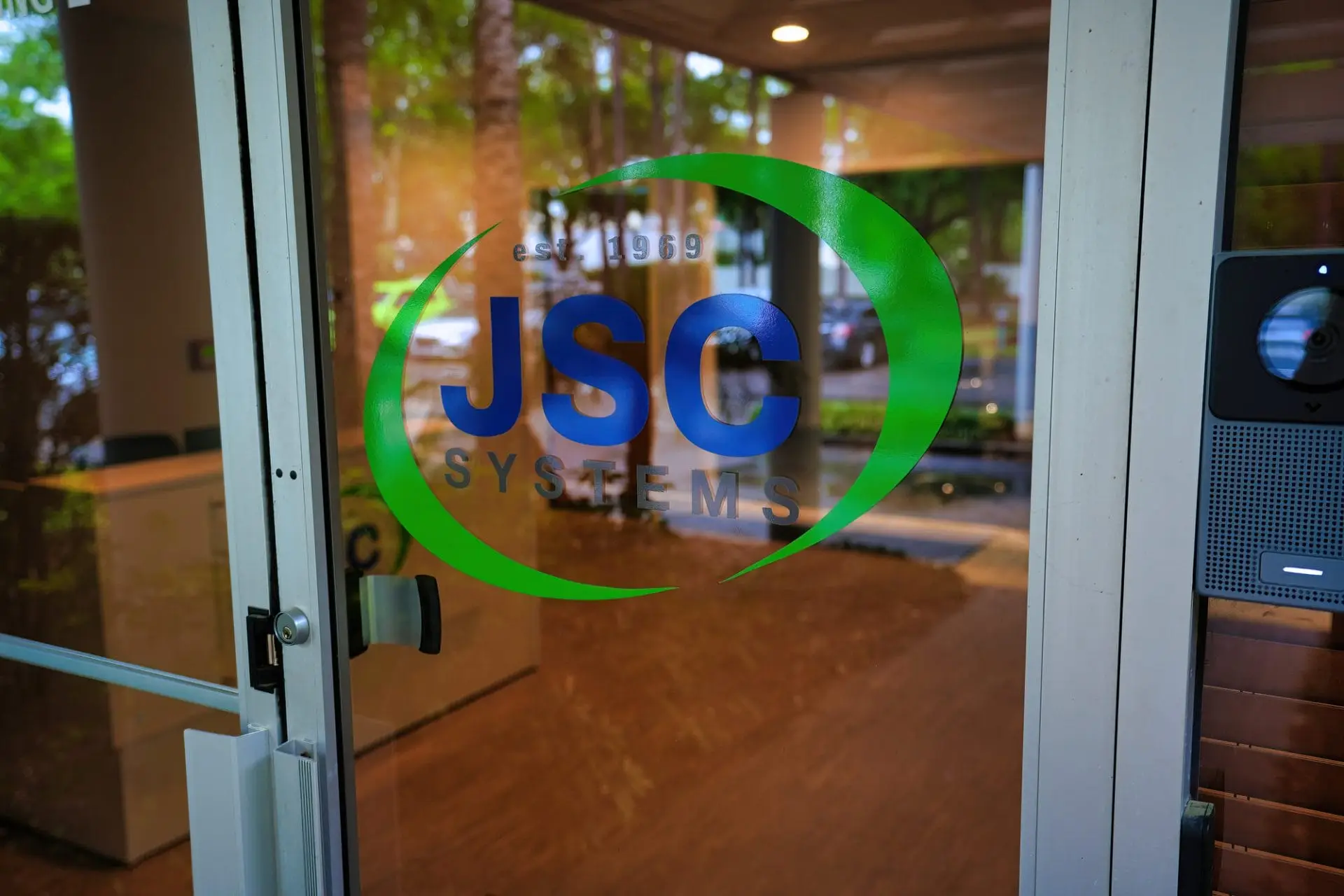 JSC Systems Low Voltage Systems team in a modern office setting, discussing project plans with digital devices and documents.